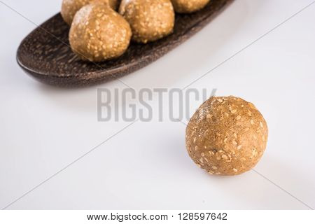 wooden plate full of tilgul laddu or til gul laddu over white background, selective focus