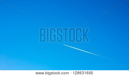 long trail of plane on blue sky as background