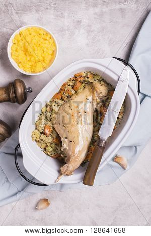 Roasted rabbit legs, vegetables stew and polenta over stone table. Top view