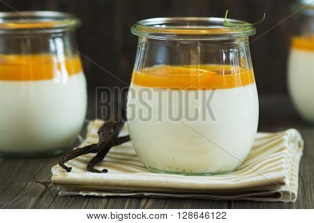 Vanilla panna cotta with exotic fruits sauce over dark wooden table. Selective focus