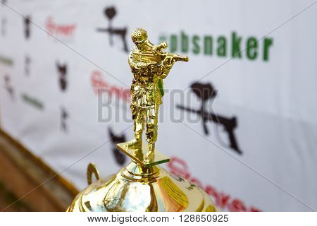 Saint-Petersburg, Russia - April 24, 2016: Paintball tournament in Snaker club between student teams from five universities. Figure of shooter on the top of golden cup.