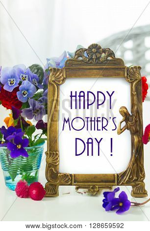 Colorful violets and pancies cut flowers, happy mother day greeting in antique frame
