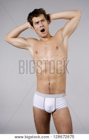 Silhouette of young adult sleepy man naked muscular torso in white panties isolated on grey background