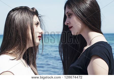Sisters At Beach Hugging Each Other. Portrait Of Beautiful Young