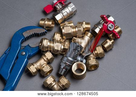 Adjustable Spanner With Assorted Plumbing Fittings On Grey