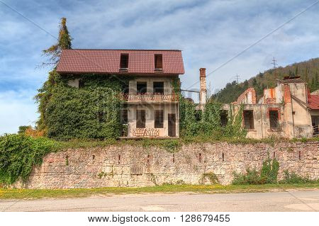 Wall of dilapidated Abaata fortress with abandoned houses over it in Gagra Abkhazia HDR processing