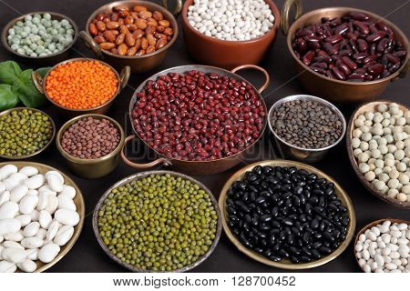 Beans peas and lentils in metal bowls.