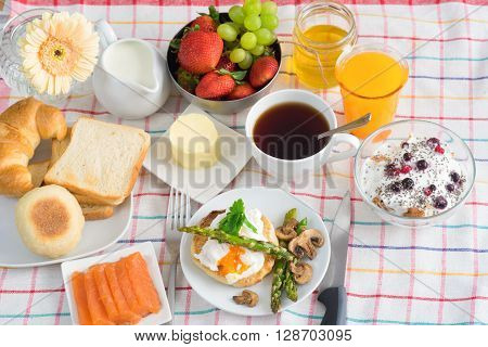 Breakfast with tea, orange Juice, poached egg, salmon, asparagus, berries, Porridge seeing from the top view