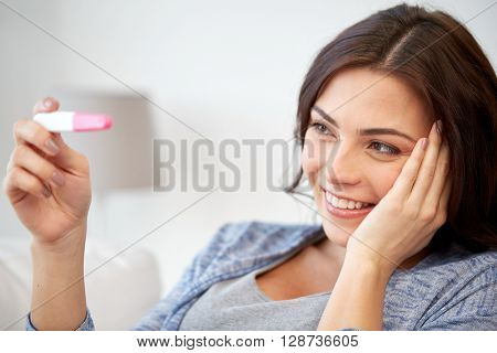 pregnancy, fertility, maternity and people concept - happy smiling woman looking at pregnancy test at home