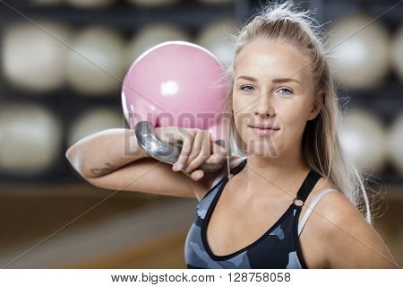 Confident Young Woman Lifting Kettlebell In Gym
