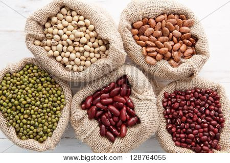 Assortment Of Beans And Lentils In Hemp Sack On Wooden Background. Green Bean, Groundnut, Soybean, R