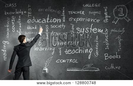 Rear view of man drawing education concept on blackboard with chalk