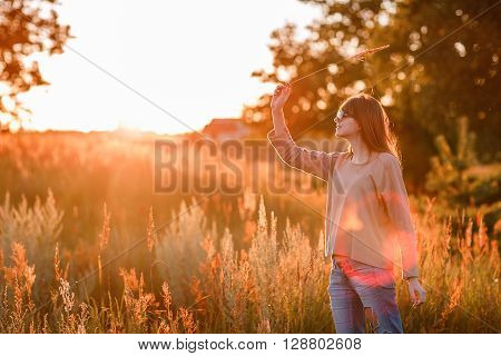 Portrait of young modern girl on the background of nature. Young woman  on a background sunset. Young woman in ripped jeans. in sun glasses