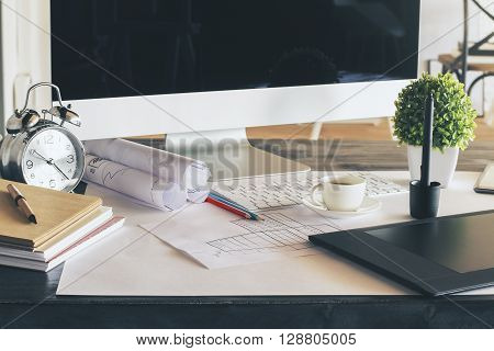 Designer desktop with computer monitor graphic tablet construction skecth and many other items