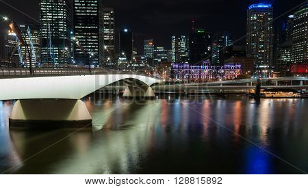Brisbane, Australia - April 27, 2016; Brisbane Victoria Bridge iluminated against dark and city building lights and colr reflections in calm water of Brisbane River