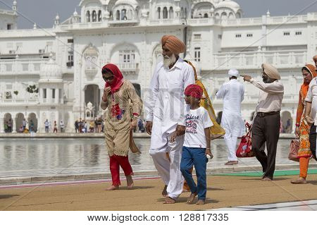 AMRITSAR INDIA - SEPTEMBER 26 2014: Unidentified Sikhs and indian people visiting the Golden Temple in Amritsar Punjab India. Sikh pilgrims travel from all over India to pray at this holy site
