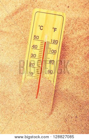 Thermometer with celsius and farenheit scale on extremely warm beach sand showing record high temperatures