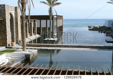 HERAKLION, CRETE, GREECE - MAY 13, 2014: The big blue swimming-pool modern building with columns palms and beach in luxury class hotel Grecotel Amirandes on the Mediterranean coast of Crete, May 13, 2014, Greece.