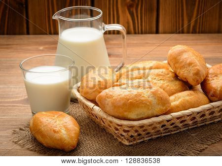 Traditional  russian pastry piroshki and milk on wooden table.