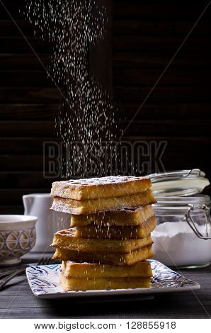 Homemade Belgian waffles with powdered sugar on a wooden background. Selective focus.