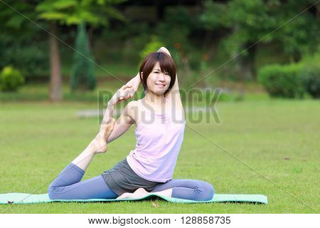 Japanese woman outside doing yoga One-Legged King Pigeon Pose