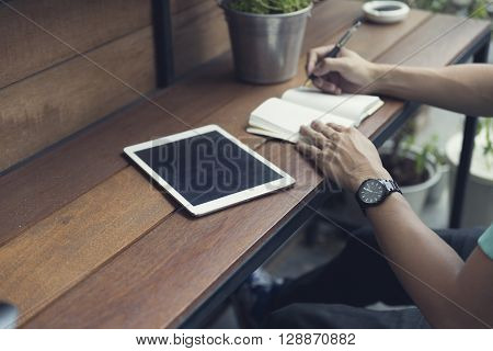 Man Writing On Notebook With Digital Tablet