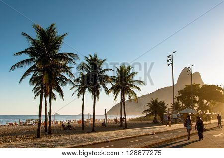 Rio de Janeiro, Brazil - March 27, 2016: People walk along a car-free Avenida Vieira Souto at sunset on Ipanema Beach.