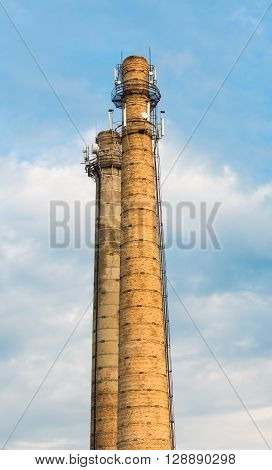Defunct industrial brick chimney against bright blue sky