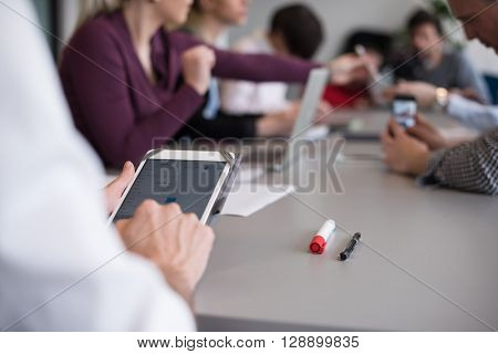 close up of  businessman hands  using tablet, people group in office meeting  room blurred in backgronud