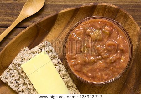 Homemade rhubarb and strawberry chutney in glass bowl with cheese sandwich on the side photographed overhead with natural light (Selective Focus Focus on the top of the chutney)