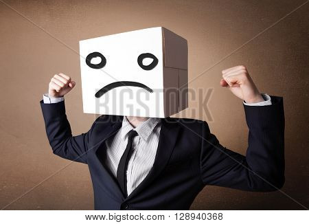 Businessman standing and gesturing with a cardboard box on his head with sad face