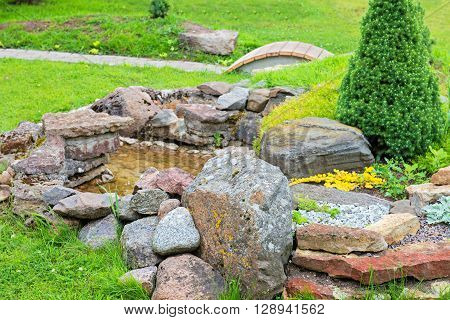 Alpine garden with bridge and small pond with water