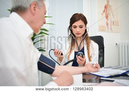 Doctor using a stethoscope and a sphygmomanometer to chec blood pressure