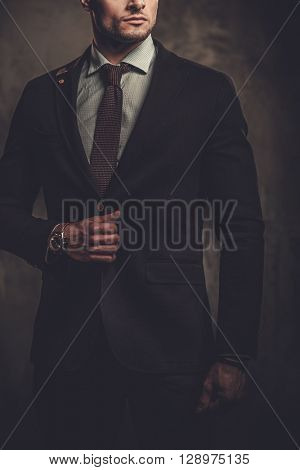 Serious well-dressed hispanic man posing on dark background. 