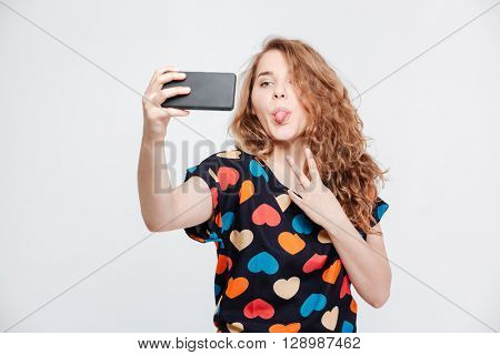 Funny woman making selfie photo on smartpone isolated on a white background