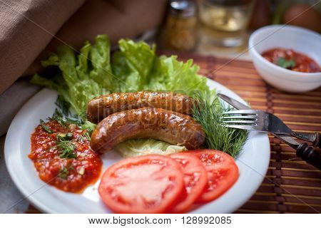 Grilled sausages with salad, tomatoes and ketchup