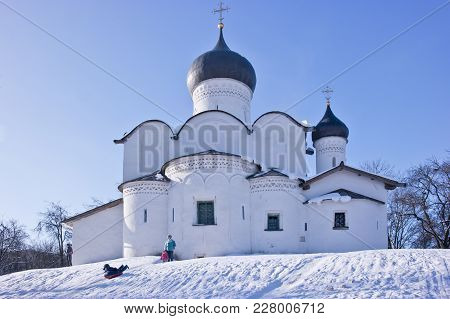 Pskov, Russia - February 21.2018: Children Riding A Snow Hill Next To The Vasilievskaya Church