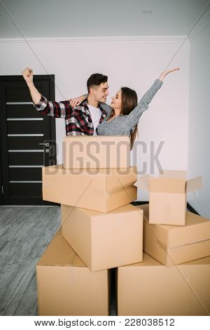 Cheerful And Happy Young Couple Victory Raised Hands Of Their New Home With Moving Cardboard Box Dur