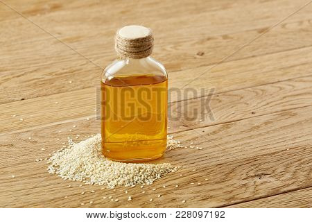 Peeled Sesame Seeds With Oil In A Small Transparent Glass Bottle Over Rustic Wooden Background, Shal