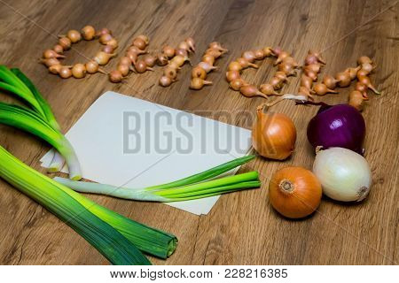 Onion, The Word Onion Is Written In Small Bulbs. Top View, Place For The Text