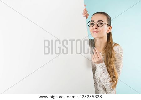 Portrait Of Attractive Happy Woman In Sweater And Round Glasses Isolated On Blue Background Holding 
