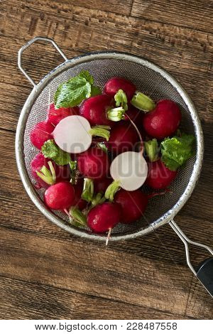 Several Washed Red Radishes In A Sieve On A Wooden Board