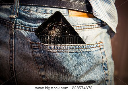 Black Smart Mobile Phone With Broken Screen In Denim Back Pocket.