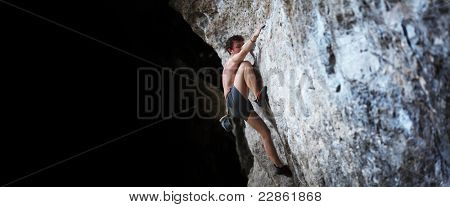 Hombre desnudo de la joven semi escalada sobre una roca sin aseguramiento
