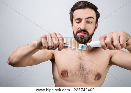 Handsome Man Is Preparing To Brush His Teeth. He Is Outting Some Tooth Paste On The Tooth Brush. Clo
