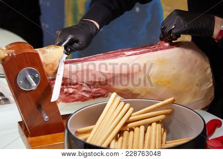 Sliced Dried Chamon Prosciutto. A Man Cuts A Jamon, A Warm Toned Image. Selective Focus Point