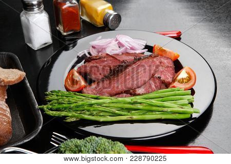 business lunch fresh roast beef meat slices on black plate wotj cutlery asparagus boiled broccoli rye bun on wooden table