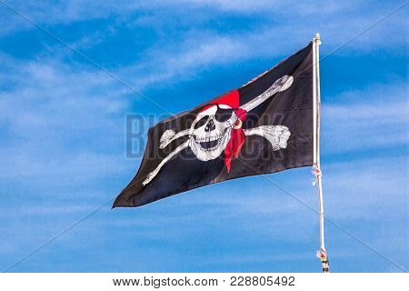 PUKET, THAILAND-FEB 2, 2016: Jolly Roger Black pirate flag with human skull on blue sky on Feb2, 2016, at Phuket, Thailand.