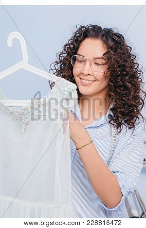 Closeup Image Of Tailor Having Made Nightgown In Arms, Ready For Sale. Being Glad Of Work