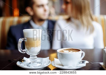 Coffee Drinks On A Table With A Pair Of Lovers In The Background